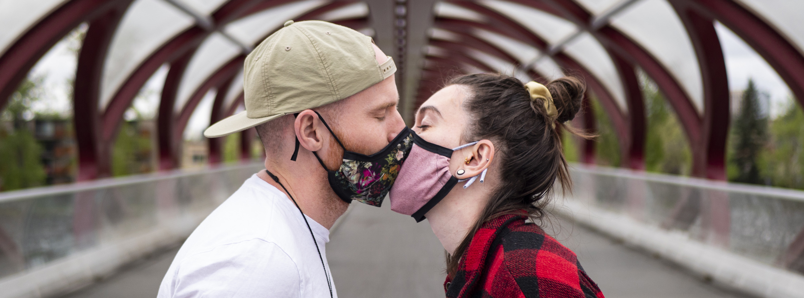 Two people kissing through face coverings