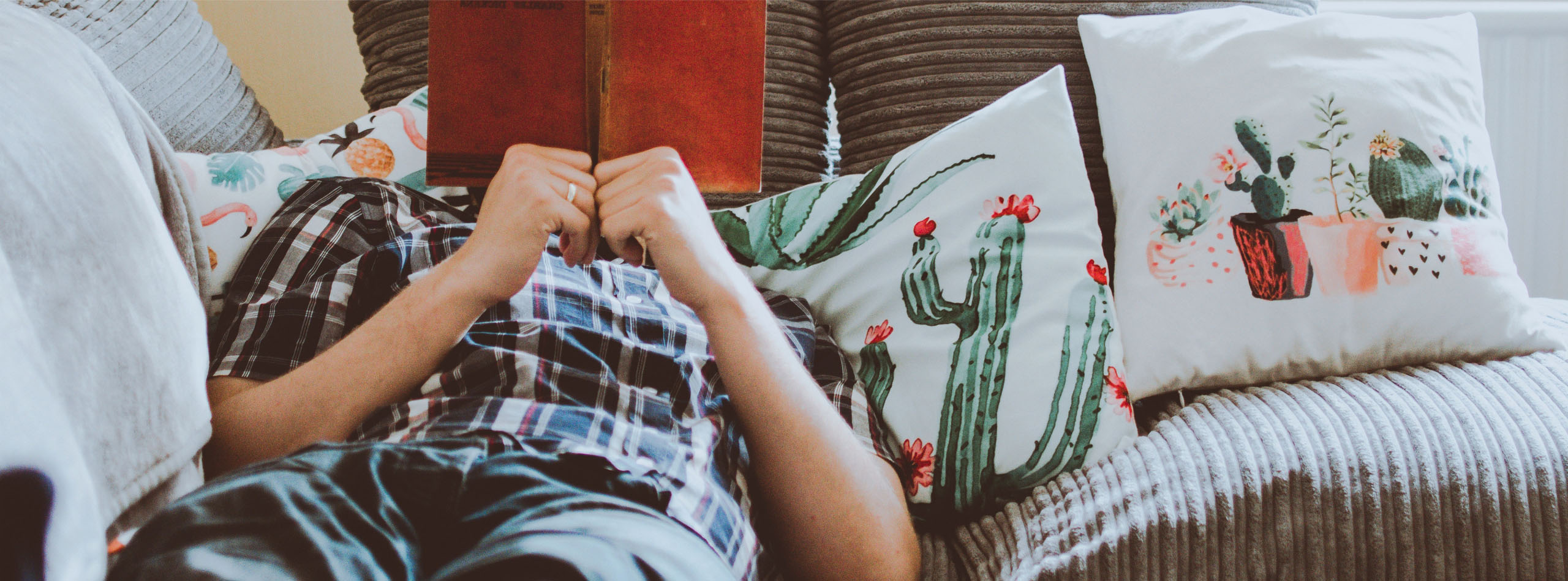 Homme qui lit un livre à côté d'un de coussins en toile coton & lin imprimés sur mesure