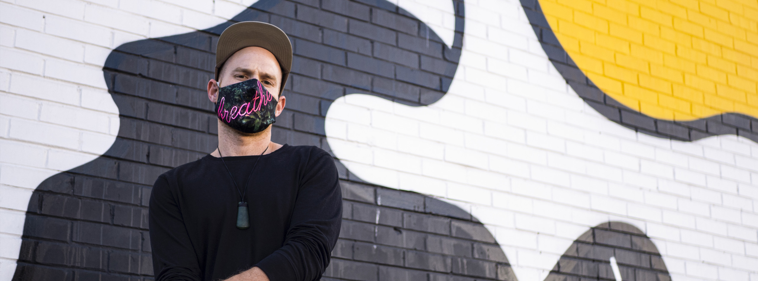 Man with custom printed face covering in front of brick wall