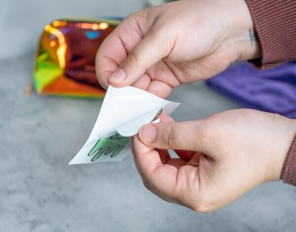 Person peeling transparent film from white backing